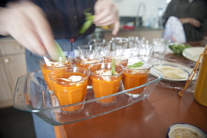 Woman Putting Basil On Tomato Soup